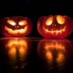 Two glowing carved pumpkins reflected on a dark surface, illustrating a guide to Halloween in London and planning a safer night out
